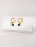 Emerald earrings with gold setting on a white background, elegant and timeless design.